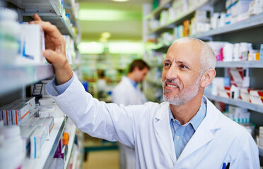 Obraz premium Happy, man and medicine in clinic for inventory, healthcare and service for retail. Man, doctor and pills or supplements in hospital for inspection, wellness and check for information or label