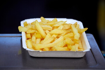 French fries in a cardboard plate. Street food
