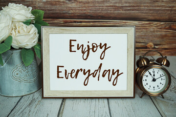 Enjoy Everyday text message with alarm clock on wooden background, Inspriation and motivationa quote