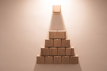Ambitions, hierarchy and leadership concept. Wooden block pyramid on beige background.