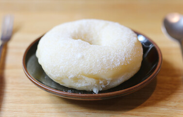 White donuts with granulated sugar on a black plate