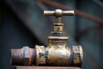 Vintage old brass water tap isolated on a dark background. tap valve. old copper retro faucet on a rusty pipe. plumbing, repair, dismantling. close-up
