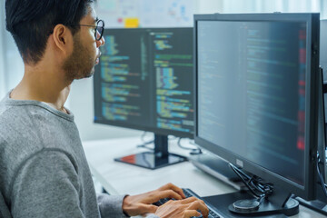 Asian man  prompt engineer develop coding app with software data sitting in front of computer monitor at office