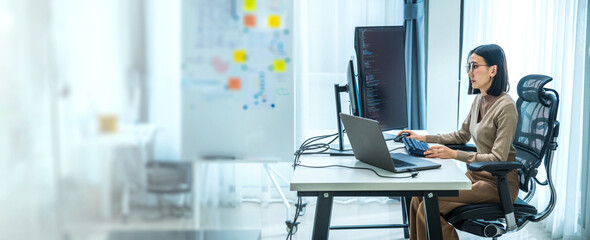 Asian prompt engineer develop coding app with software data sitting in front of computer monitor at...