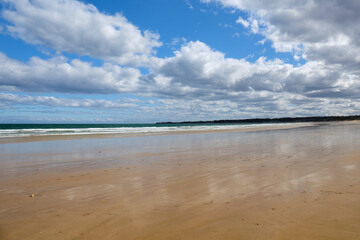 The sky and the clouds are reflected on the wet sand at low tide - Torquay, Victoria, Australia