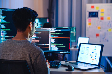Asian software developers working on multiple screens displaying code and application diagrams at...