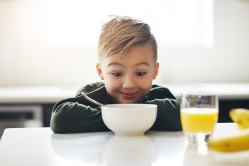 Excited, breakfast and kid in kitchen for morning, nutrition and health for development. Happy, child and bowl for cereal with orange juice for vitamins, growth and wellness on weekend in home