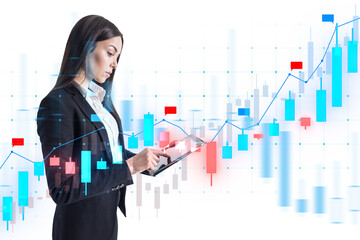 A businesswoman analyzing financial data over a graph interface, with a blurred white background indicating technology and analysis