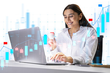 A businesswoman analyzing financial graphs on a transparent futuristic interface, with a laptop in front of her on a white background. Concept of modern finance analysis
