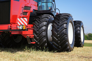 Obraz premium Front view of a large red tractor standing in a field. New model of agricultural equipment.