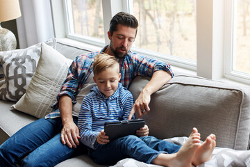 Father, boy and tablet on couch with internet for educational gaming, movie bonding and online tv...