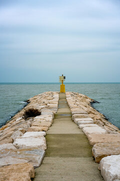 Yellow lighthouse on a stone pier in Rimini, Italy