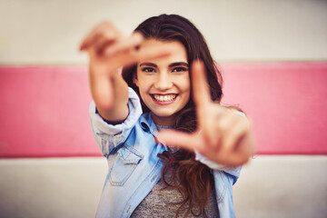 Portrait, hands and girl in city, frame and happiness, with selfie, social media and getaway trip. Face, person or woman with wall background, gesture and excited for memory, picture or photography