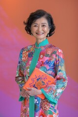 Portrait of an Asian woman in a colorful floral patterned dress, holding a book