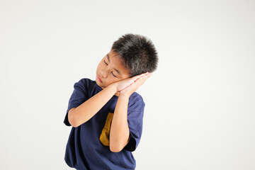 Portrait Asian young kid boy pretended emotions sleeping tired eyes closed dreaming with hands together near face, studio shot on white background, with copy space, insomnia concept, primary child