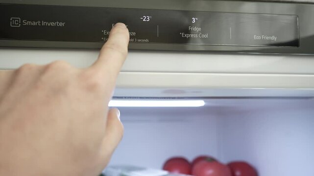 A man's hand regulates the temperature of the refrigerator and freezer. Close-up. Modern gray stylish refrigerator. Optimal food storage temperature. High quality 4k footage