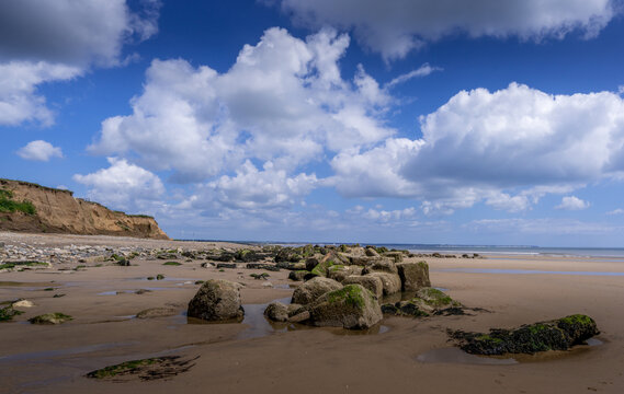 Barmston Beach in East Yorkshire. Low tide exposes a sandy beach covered with large rocks and boulders.
