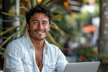 Fototapeta premium Man Smiles While Using Laptop At An Outdoor Cafe