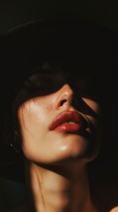 A woman with dark hair wears a hat, her face lit by sunlight streaming through a window
