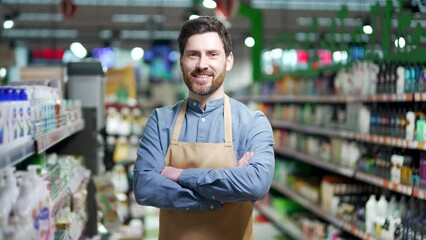 Portrait man worker in supermarket grocery store or deli in apron look at camera Male sales manager small business owner Happy smiling handsome employee in food market hypermarket friendly arm crossed