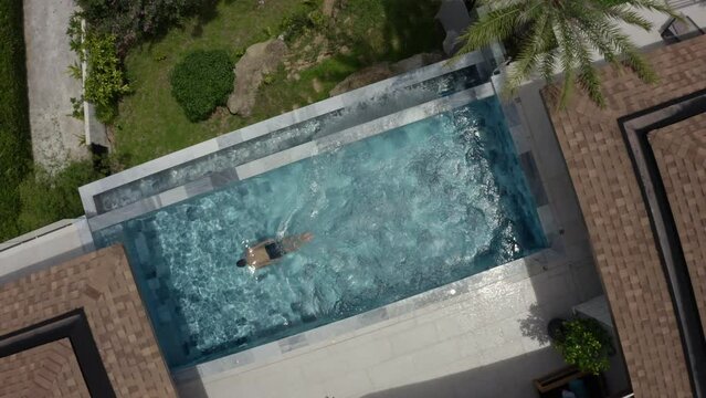 Enjoy the aerial view of a luxurious backyard swimming pool in a beautiful summer setting