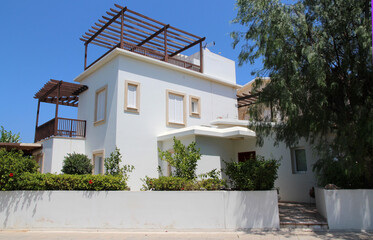 White house, villa, apartment in Mediterranean Greek style in the middle of greenery and flowering garden on a sunny summer day in Cyprus