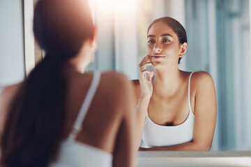 Woman, mirror and touch face in bathroom for skincare, results and beauty or cleaning. Female person, reflection and skin in house for facial texture and dermatology after microneedling aftercare