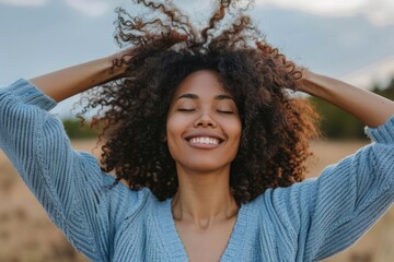 joyful woman with her arms raised and eyes closed, smiling broadly