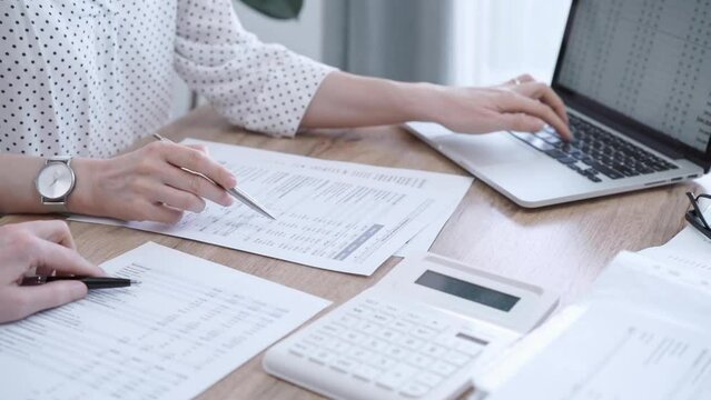 Professional female bookkeeper with a colleague are working on business finances. using calculator and laptop. Finance audit and taxes