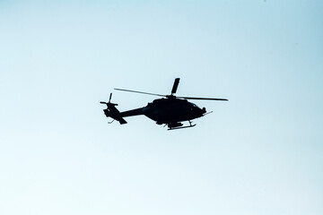 Silhouette helicopter is flying on isolated blue sky 