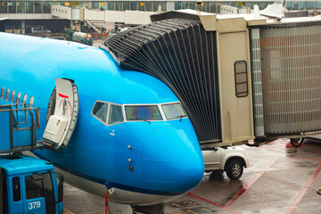 A passenger plane stands on the airport grounds at the passenger landing area with a passenger...