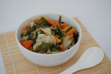Capcay in a white bowl on a bamboo mat