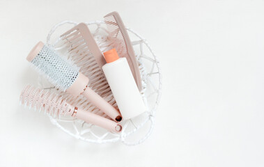 Different hair combs and plastic bottle on white background. The concept of hair care. Template for cosmetics products.