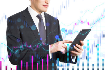 A businessman using a tablet with financial charts overlaid in the background, representing analytics and technology