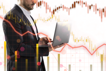 A businessman using a laptop with overlaid financial graphs and data, symbolizing market analysis on a white background with light hue