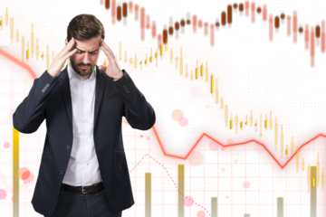 Man in distress with hands on head against a background with stock market graphs, concept of financial stress or crisis