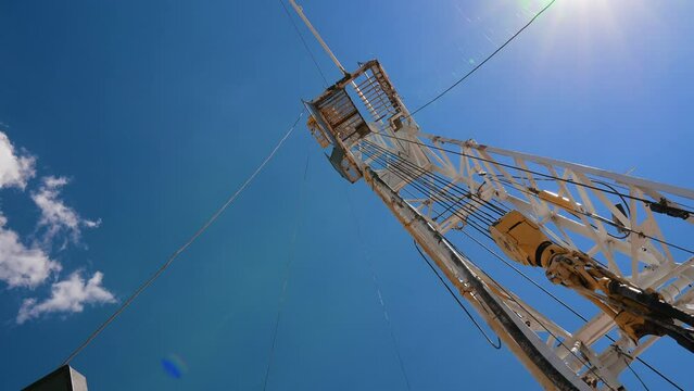 High derrick at the site for drilling natural resources. Low angle view on the rig tower for oil production.