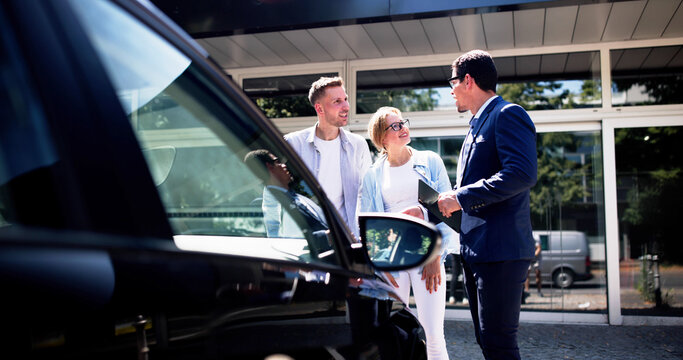 Professional Car Saleswoman Assisting Happy Hispanic Couple with Purchase