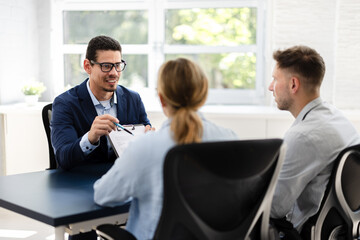 Financial consultant explaining new project investment to young couple in office