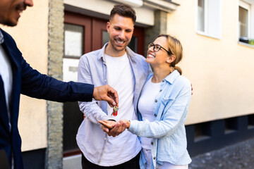 Fototapeta premium Real estate agent handing over keys to a young couple for their new home