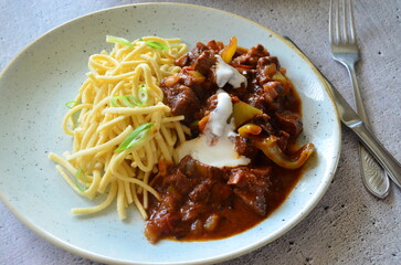 family meal background, served food, beef perkelt, spaetzle, blue plate, top view