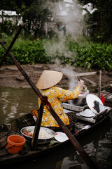 A Vietnamese woman selling pho on the Phong Dien floating market in Vietnam