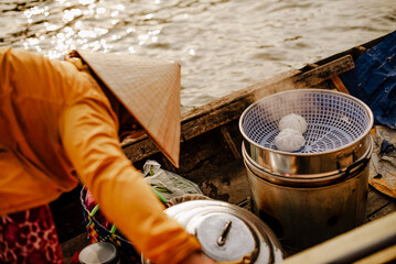 A woman selling banh baos on the Cai Rang floating market in Vietnam