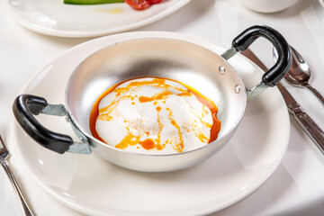Poached egg Turkish name Cilbir, a classic Turkish dish, on a metal plate
