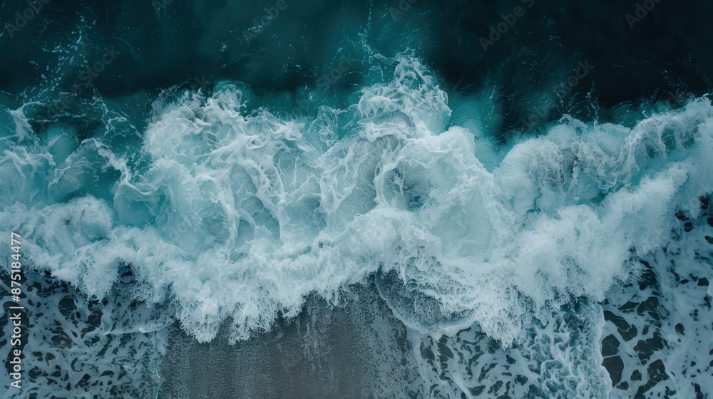 Poster an overhead perspective showing ocean waves rolling into shore, with the interplay of foam and surf 