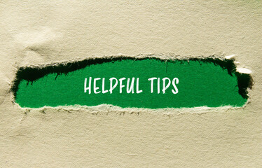 Helpful tips message written on ripped torn paper with green background. Conceptual helpful tips symbol. Copy space.
