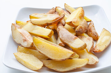 Close up of fresh made fried potato chunks on a piece of baking paper. Healthy food concept.