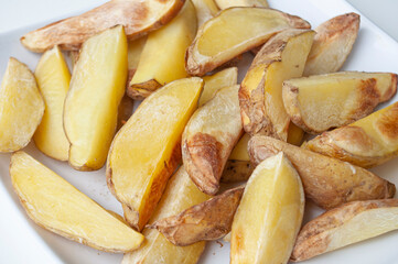 Close up of fresh made fried potato chunks on a piece of baking paper. Healthy food concept.