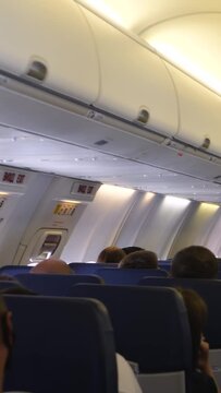 Passengers sits on seats aircraft while flying. Stewardess inside cabin of commercial plane while flight. Air traveling by commercial airplane. Economy class