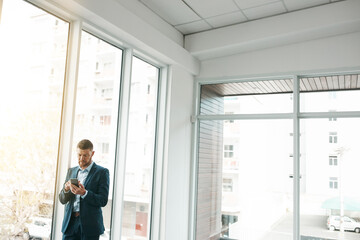 Fototapeta premium Business, empty office and man with smartphone for email or communication and networking. Entrepreneur, property and serious for online or digital application with funding for startup company
